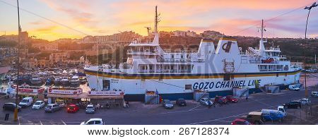 Ghajnsielem, Malta - June 15, 2018: Panorama Of The City On Sunset With A View On The Ro-ro Ferry An