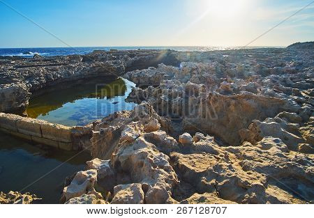 The Evening Sun Is Warming Unapproachable Coast With Sharp Rocks And Tiny Backwaters, Dwejra, San La