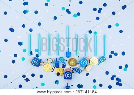 Blue Confetti  Background With Menora Made Of Dreidels And Chocolate Coins. Hanukkah And Judaic Holi