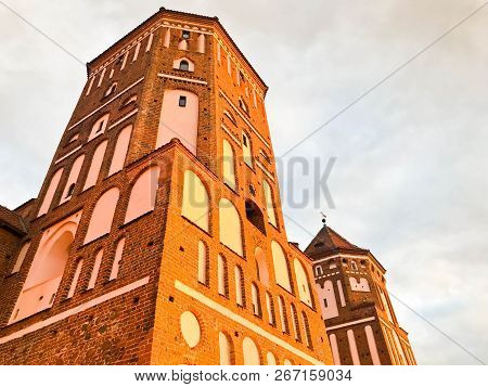 Towers And Spiers Of A High Medieval Stone Old Ancient Beautiful Castle Against A Blue Sky.