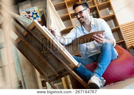 Young Handsome Smart Man Painting On Canvas