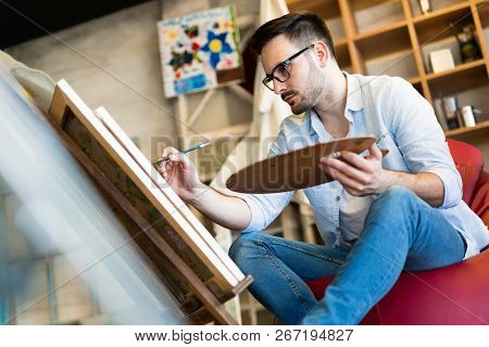 Young Handsome Smart Man Painting On Canvas