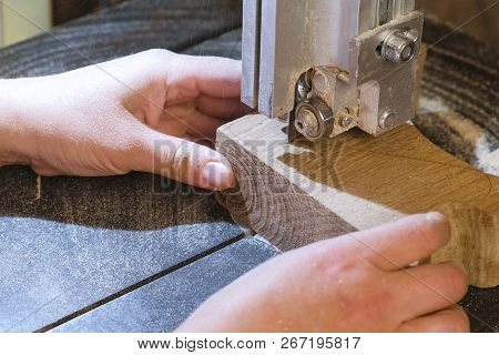 Craftswoman Is Cutting A Wood Workpiece From Wood With Bandsaw. Close-up Hands.