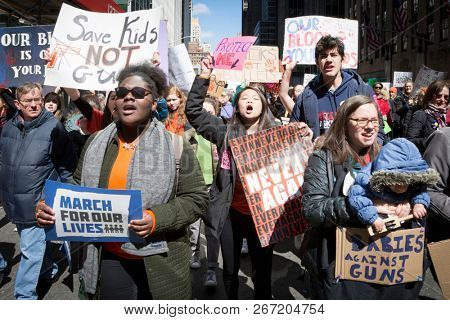 March For Our Lives: Participants, including a woman holding an infant, in the march to end gun violence on 6th Ave hold signs with various phrases, NEW YORK MAR 24 2018.