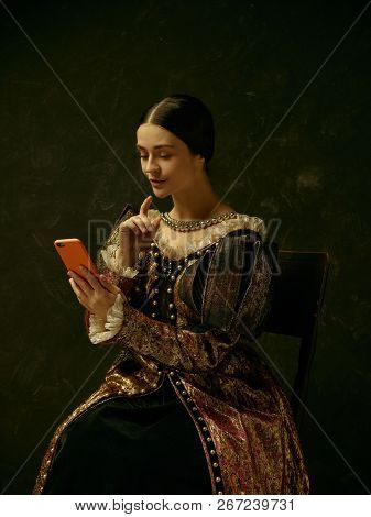 Portrait Of A Girl Wearing A Princess Or Countess Dress With Mobile Phone Over Dark Studio Making Se