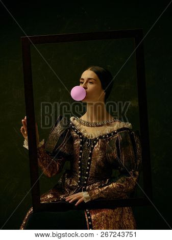 Portrait Of A Girl Wearing A Princess Or Countess Dress Over Dark Studio. Portrait Through Picture F