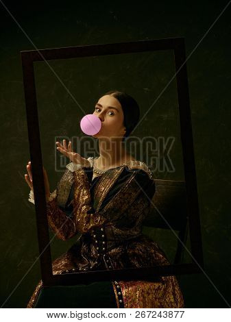 Portrait Of A Girl Wearing A Princess Or Countess Dress Over Dark Studio. Portrait Through Picture F