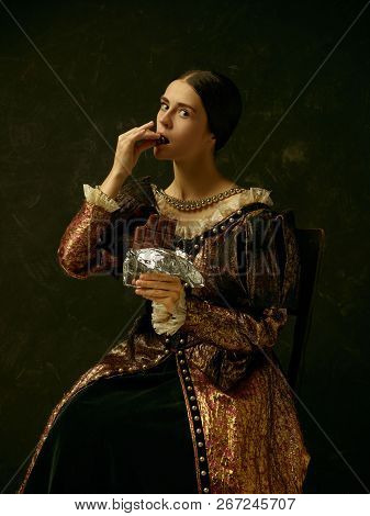 Portrait Of A Girl Wearing A Princess Or Countess Dress Over Dark Studio. Portrait With Sweet Chocol