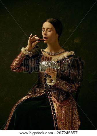 Portrait Of A Girl Wearing A Princess Or Countess Dress Over Dark Studio. Portrait With Sweet Chocol