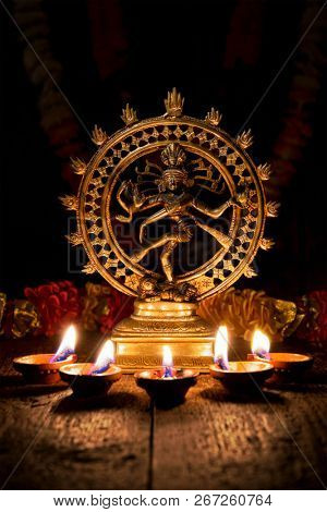 Maha Shivaratri or Diwali concept - Shiva Nataraja figurine with Diwali lights oil ghee candles, India