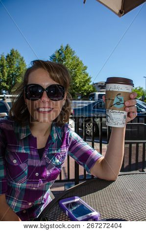September 1 2018 - Duluth, Mn: Smiling Adult Female Enjoys A Cup Of Caribou Coffee While Sitting Out