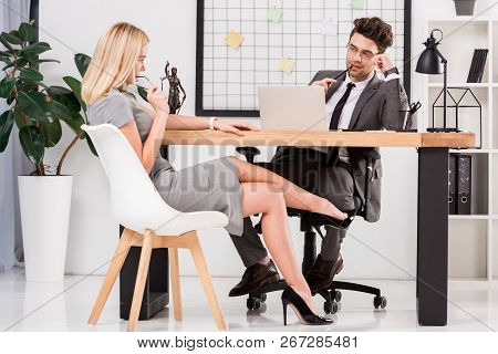 Young Businesswoman Flirting With Business Colleague At Workplace With Laptop In Office