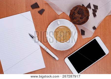 White Porcelain Cup Of Coffee, Tasty Chololate Muffin, Pieces Of Black Chocolate On Pergament Paper,
