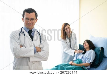 Portrait Of Profressional Doctor With Stethoscope While Female Doctor Take Care Her Patient.