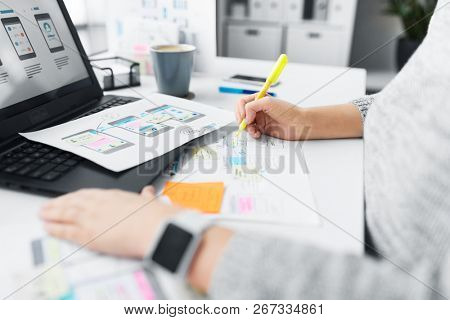 app design, technology and business concept - web designer or developer with sketches and laptop computer working on user interface at office