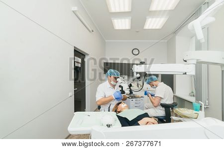 Doctor Used Microscope. Dentist Is Treating Patient In Modern Dental Office. Operation Is Carried Ou