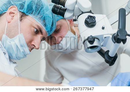 Doctor Used Microscope. Dentist Is Treating Patient In Modern Dental Office. Operation Is Carried Ou