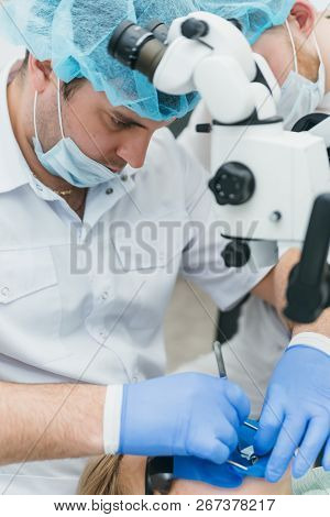 Doctor Used Microscope. Dentist Is Treating Patient In Modern Dental Office. Operation Is Carried Ou