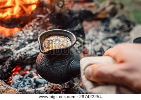 Boiling Coffee In Turkish Cezva On Campfire Coals. Luxury Camping Concept.