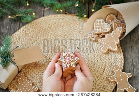 Womens Hands Hold Homemade Christmas Gingerbread Cookies With Sugar Frosting On A Beautiful Wooden B