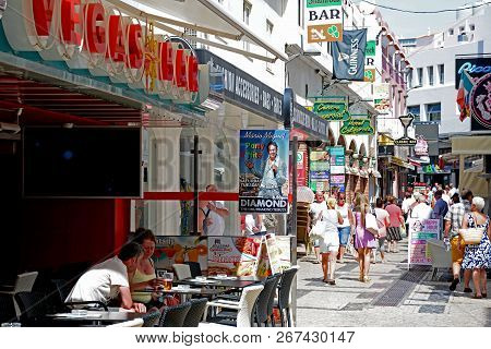 Albufeira, Portugal - June 10, 2017 - Tourists Relaxing At A Pavement Cafe In The Old Town With Shop