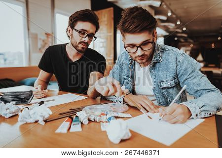 Portrait Of Two Painters Sit At Desk And Drawing. Talanted Freelance Artists Painting At Table Focus