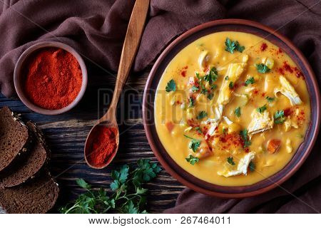 Overhead View Of Hearty Pumpkin Carrot Chicken Breast Creamy Soup In An Earthenware Bowl On A Rustic