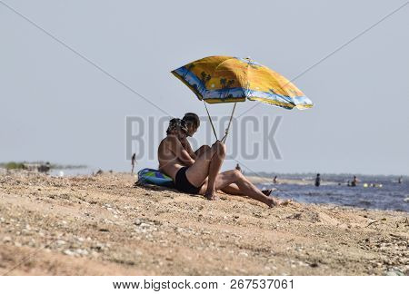 Anapa, Russia - July 17, 2017: Two Gay Men On The Beach Under An Umbrella. Homosexual Couple On The 