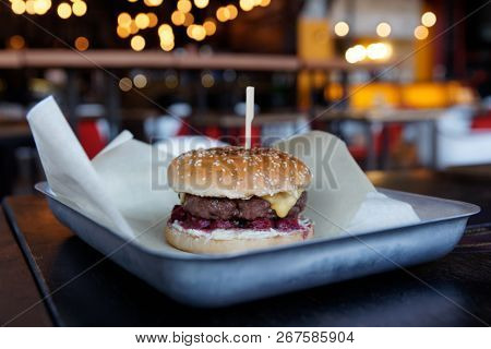 Burger with marinated cherry and chedder cheese on restaurant table, cool tone