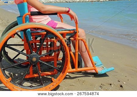 Little Girl On The Wheelchair With Special Metal Wheels To Go On The Beach