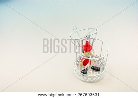 Metal Cage And Little Puppet Pinocchio Made Of Wood