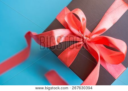Brown Gift Box With Red Ribbon On Blue Background. Top View With Copy Space.