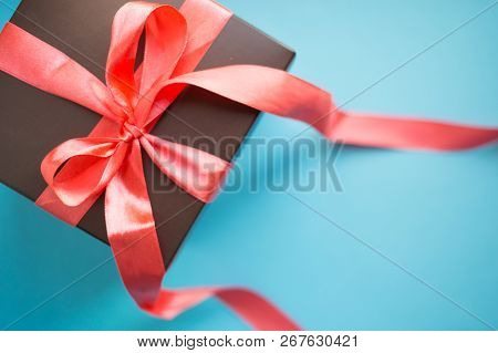 Brown Gift Box With Red Ribbon On Blue Background. Top View With Copy Space.