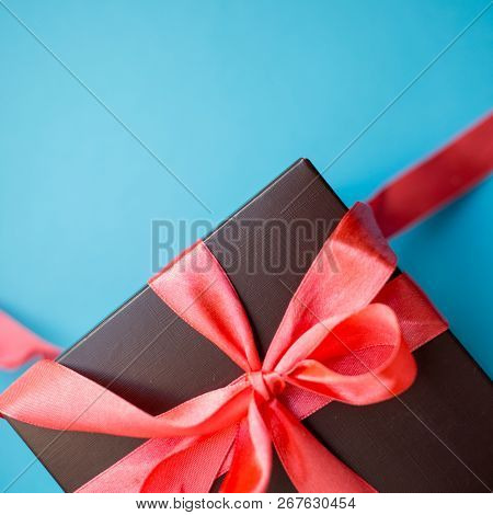 Brown Gift Box With Red Ribbon On Blue Background. Top View With Copy Space.