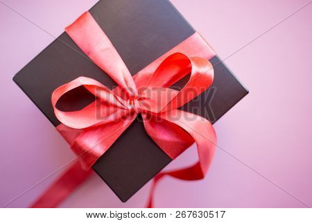 Brown Gift Box With Red Ribbon On Pink Background. Copy Space.