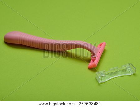 Pink Disposable Razor For Depilation On A Green Background.