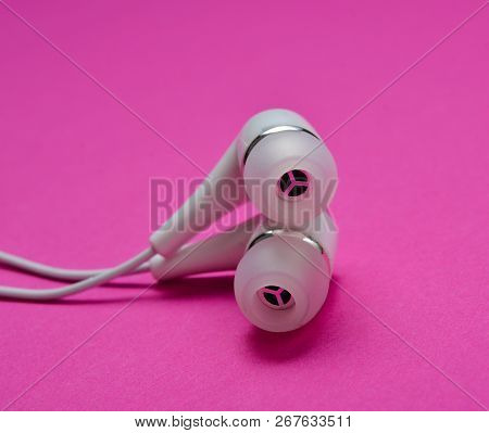 White Vacuum Headphones Close-up On A Pink Background.
