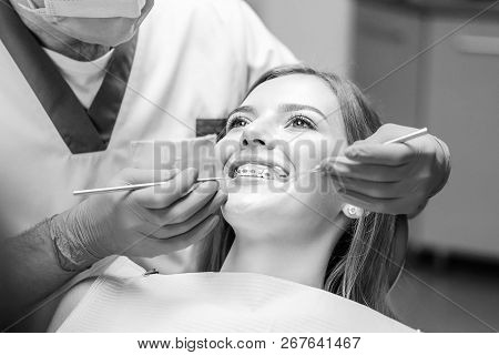Dentist Examine Female Patient With Braces In Denal Office.
