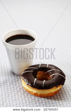 Chokolade top doughnut og sort kaffe på en bordplade
