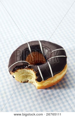 En chokolade omfattet doughnut med en bid, taget fra den.