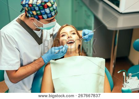 Dentist Examine Female Patient With Braces In Denal Office.
