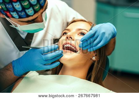 Dentist Examine Female Patient With Braces In Denal Office.