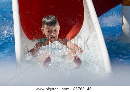 Boy Sliding Down From Waterpark Flume On Vacation.