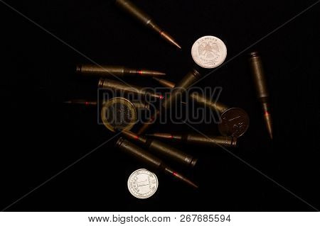 One Euro, One Russian Ruble And Ukrainian Hryvna Coins With Rifle Military Ammo On Black Background.