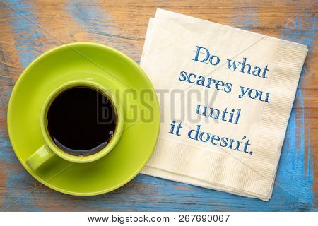 Do what scares you until it doesn't - inspirational handwriting on a napkin with a cup of coffee