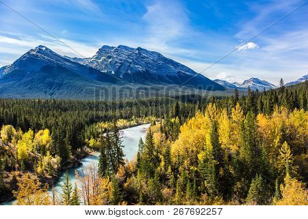 The lake is surrounded by colorful autumn forest. The picturesque Abraham lake in the mountain valley of the Rockies of Canada. Concept of active, ecological and photo tourism