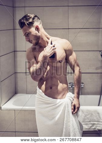 Young Man In Bathroom, Spraying Cologne Or Perfume