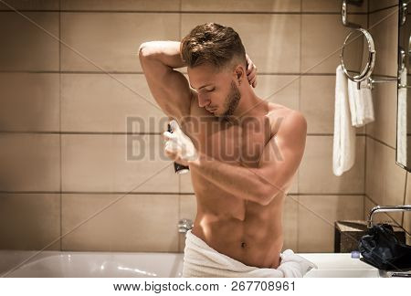 Young Man In Bathroom, Spraying Deodorant On Armpits