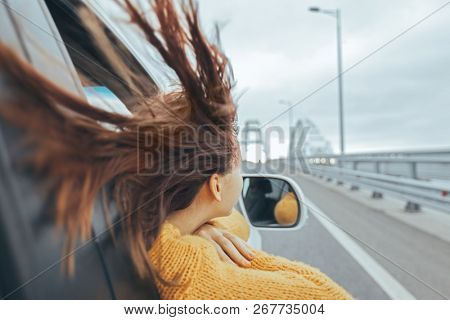 Rear view of pre teen girl in car looking forward on a bridge at weekend road trip