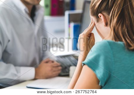 Woman Suffering From Bad Headache Or Migraine. Appointment With Doctor In Office Room. Sick And Unwe